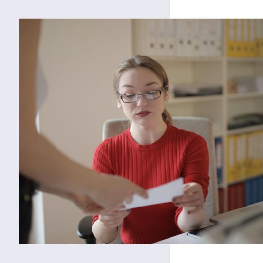 A woman sitting at a desk, holding a piece of paper | RM Recruitment